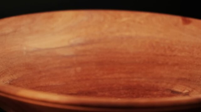 Roasted coffee beans dropping and bouncing into a large wooden bowl
