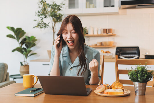 Happiness Entrepreneur beautiful business asian young woman wear casual use mobile phone for shopping online enjoy with social media and laptop at home.Small Business Startup.online banking