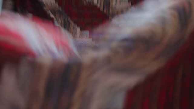 Close-up of hands shaking out heavy red quilt over bed on floor