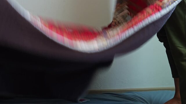 Man handling traditional patterned blanket during bedroom routine