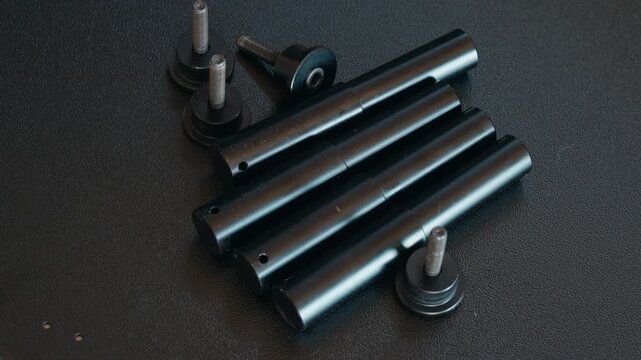 Slow zoom out close-up of black specialty bolts and fasteners arranged on a black metal surface in a workshop setting
