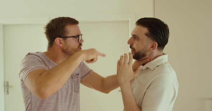 An aggressive man grabs another man by the neck during a heated confrontation. Concept of conflict, intimidation, aggression, domestic dispute, and violence.