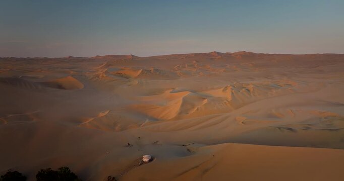 Vast sandy Peruvian dune landscape surrounding Huacachina. Golden hour aerial