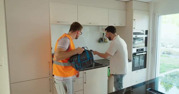 A homeowner welcomes a service technician carrying a toolbox for a home repair visit. Concept of maintenance, technical support, and professional repair service.