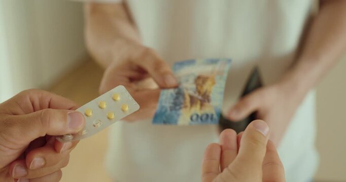 Close-up of an illegal drug transaction involving pills and cash. Concept of drug trafficking, narcotics, organized crime, and law enforcement.