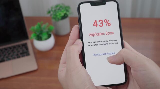 Hands hold a smartphone displaying an AI alert with a 43 percent job application score and an option to improve the application.
