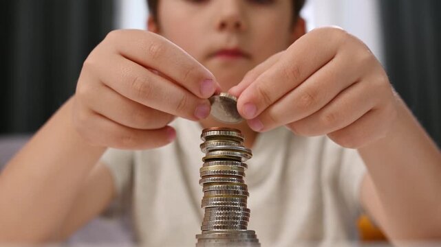 Focused child building stacks of coins on table as part of practical financial education, teaching importance of budgeting, saving and making thoughtful financial choices.