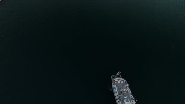 Aerial view of a traditional phinisi boat sailing on calm dark waters near the coast of Labuan Bajo, Komodo, East Nusa Tenggara, Indonesia.