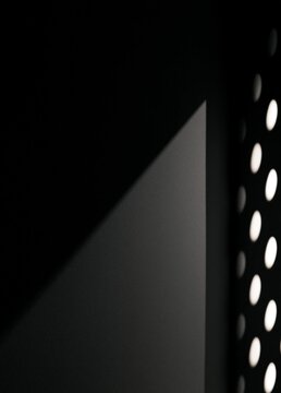 Black and white photograph of a corner of a room. the corner is in the center of the image, with a dark grey wall on the left side and a white polka dot pattern on the right side.