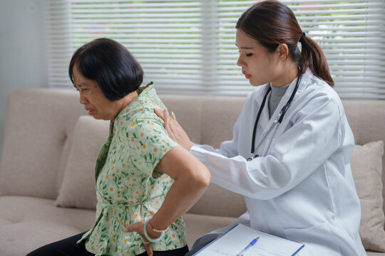 Doctor examining elderly patient having back pain at home