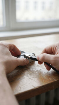 Close up of hands connecting a USB cable to a device by an office window
