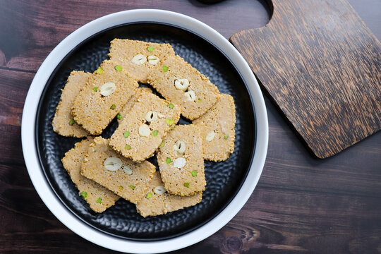 Til gajak, a traditional Indian winter sweet made with sesame seeds, jaggery, ghee, and dry fruits. Crunchy til chikki, a festive treat for Makar Sankranti. Tilgul. Sesame candy. Copy Space. Winter fo