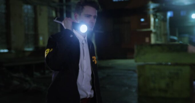 Shot begins with a close-up of wooden beams before revealing an FBI agent cautiously walking through a dark wet alley.