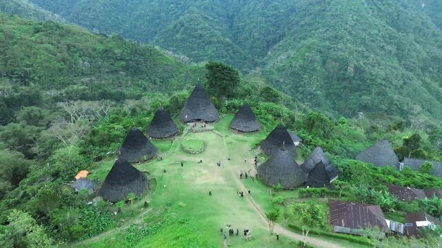 Aerial view of the traditional conical houses of Waerebo Village nestled in the lush green mountains of Satar Mese Barat, East Nusa Tenggara, Indonesia.