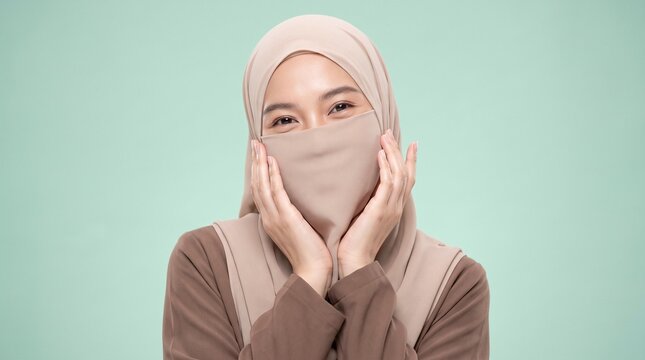 Portrait of a smiling young Muslim woman wearing a traditional hijab and niqab covering her face against a solid green background.