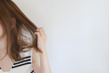毛先を確認する女性 © webbiz