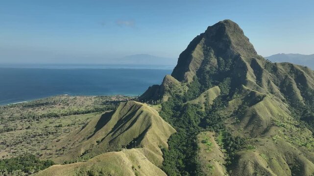 Aerial view of the rugged Nuca Molas mountain landscape with lush green slopes and coastal scenery in Satar Mese Barat, East Nusa Tenggara, Indonesia.