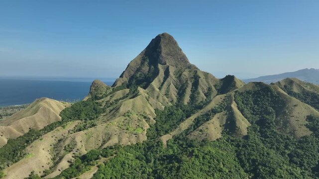Aerial view of Nuca Molas mountain with sharp ridges and lush green slopes rising above the sea in Satar Mese Barat, East Nusa Tenggara, Indonesia.