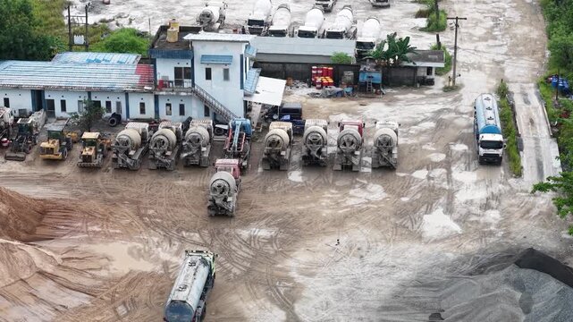 Aerial view of cement mixer trucks parked in a row and piles of raw materials for cement production