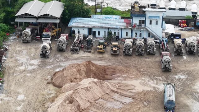 Aerial view of cement mixer trucks parked in a row and piles of raw materials for cement production