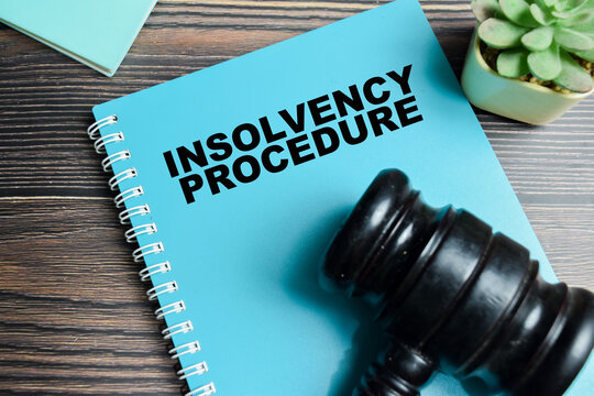 Concept of insolvency procedure on book with judge gavel isolated on Wooden Table.