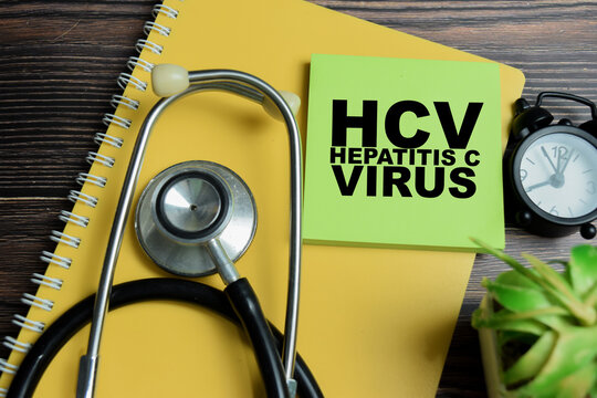 Concept of HCV - Hepatitis C Virus write on sticky notes with stethoscope isolated on Wooden Table.