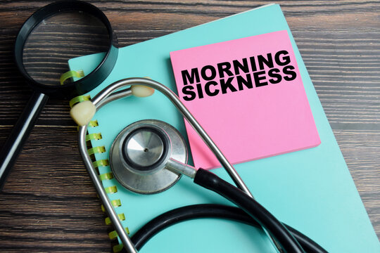Concept of morning sickness write on sticky notes with stethoscope isolated on Wooden Table.