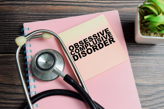 Concept of obsessive compulsive disorder write on sticky notes with stethoscope isolated on Wooden Table.