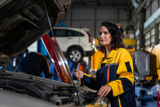 female mechanic or engineer in workwear checking car engine to diagnostic and repair in auto services
