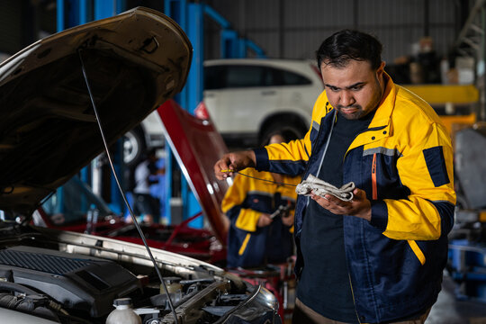 Indian male mechanic in workwear checking car engine to diagnostic and repair in auto services