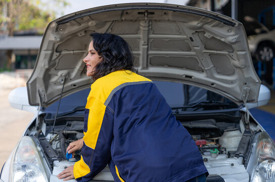 female auto mechanic inspecting vehicle engine for maintenance service