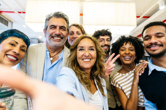 Happy people smiling and posing for a group selfie, celebrating collaboration and success in a modern office workplace
