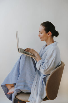 Side View Of Woman Sitting On Chair Working Focused On Laptop Computer In Light Blue Shirt