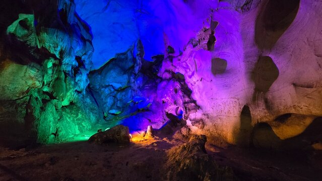 Magical underground cave chamber lit by a rainbow of vibrant neon spotlights