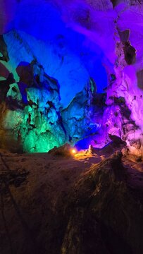 Spectacular subterranean cave vault illuminated by multicolored neon lights and glowing torch