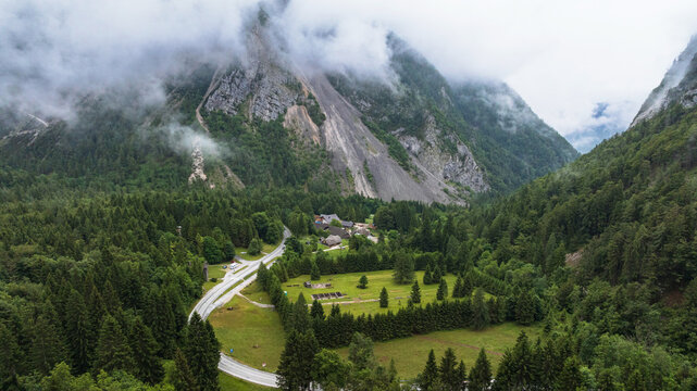 Spectacular drone overview reveals high mountain ridges along border of Austria and Slovenia. Massive Alpine peaks, deep valleys, and evergreen forests dominate majestic European landscape.