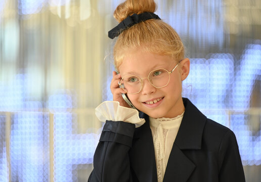 Close-up portrait of a little girl smiling happily and talking on the phone