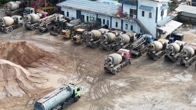 Aerial view of cement mixer trucks parked in a row and piles of raw materials for cement production