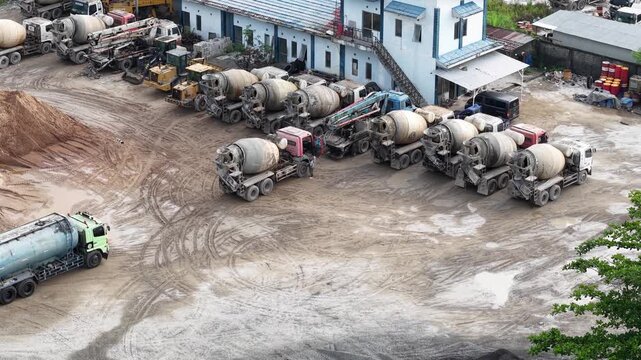 Aerial view of cement mixer trucks parked in a row and piles of raw materials for cement production