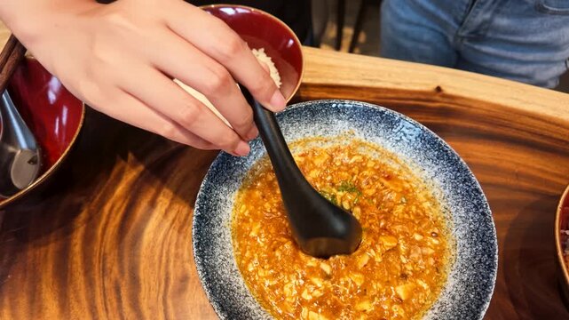 Person Scooping Spicy Mapo Tofu Stew with Black Spoon