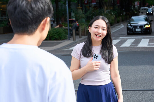 Young Japanese Man and Woman Waving and Greeting Each Other on City Street