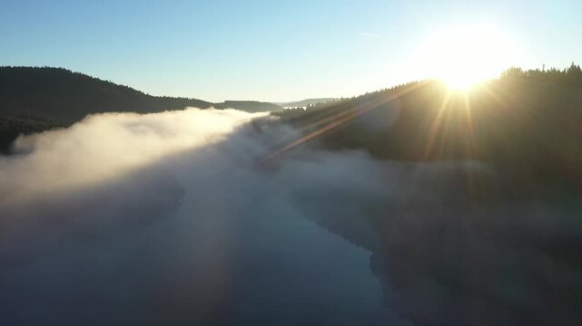 Slow motion aerial shot above the clouds and moving mist with sunrise in the morning time