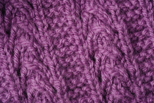 Purple knitted fabric close up with cable knit pattern