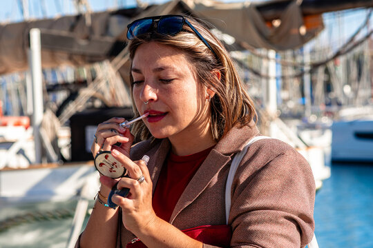Woman applying lip gloss at port of barcelona