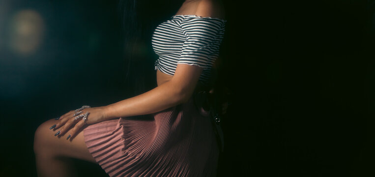 Young beautiful woman in a dress posing in a dark room.