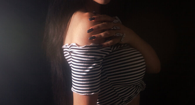Young beautiful woman in a dress posing in a dark room.