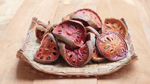Dried bael fruit slices placed on a wooden surface.