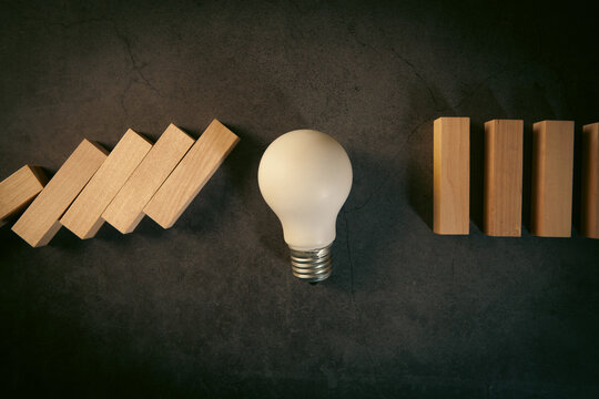 Idea concept with light bulb and wooden blocks on black background.