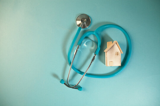 Stethoscope and model of a house on a blue background. Health care concept.