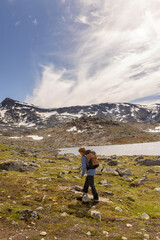 Obraz premium Beautiful european family with children and pet dog, hiking Kyrkja mountain on a beautiful sunny summer day, sunset, snow, lakes, valley
